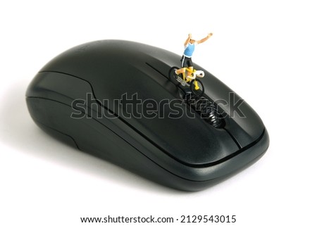Miniature people toy figure photography. Creative concept. A biker cycling above black mouse, isolated on white background. Image photo