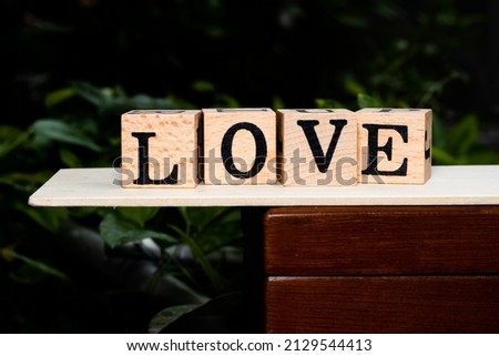 Wooden alphabet blocks arranged into "love" on a wooden box.