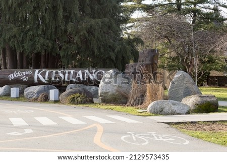 Welcome to Kitsilano sign on huge tree trunk seen next to bicycle path and pedestrian crossing during a winter afternoon, Vancouver, British Columbia, Canada