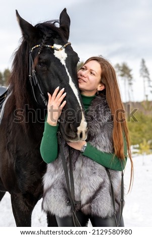 Girl on a black horse. Walk with a horse through the countryside. Russia. Lipetsk 20.02.2022.redhead girl