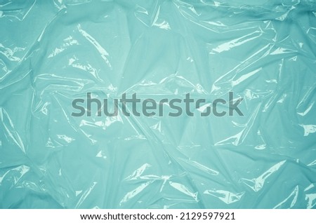 Plastic wrap texture for overlay. wrinkled stretched plastic effect. transparent plastic wrap on turquoise background. Food rumpled cellophane wrap