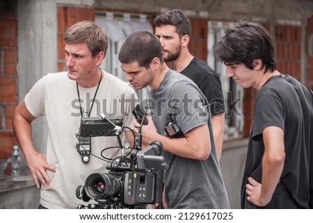 Behind the scenes. Film crew team shooting movie scene on outdoor location. Group filmmaking set production