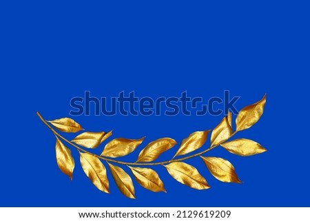 Golden  yellow branch with dry natural coloured leaves on a blue background depicting peace in the world Royalty-Free Stock Photo #2129619209