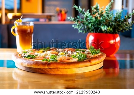 italian pizza with tomatoes, cucumber, chicken and peppers on a table with a cocktail at sunset