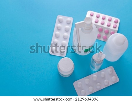 medical preparations such as pills and sprays on a blue background. Flat lay, mockup and copy space.