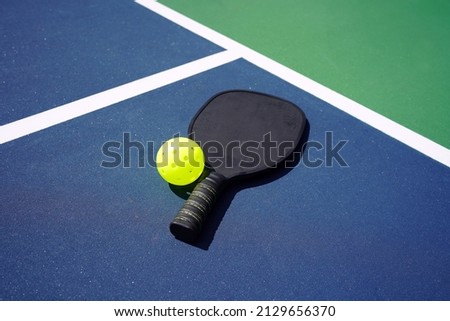 Pickleball Paddle and pickle ball of court.                          Royalty-Free Stock Photo #2129656370