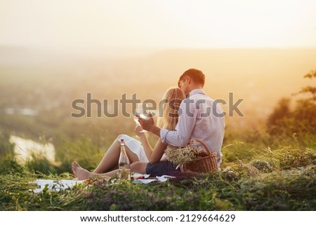 A young romantic couple having a picnic on the hill with some food and wine. Royalty-Free Stock Photo #2129664629