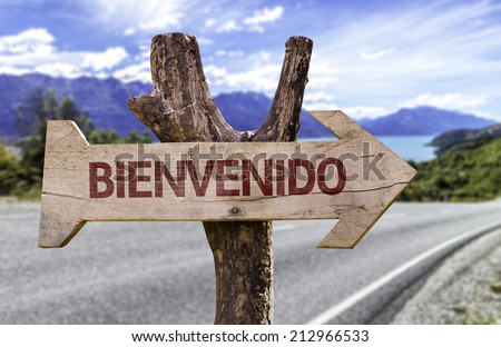 "Bienvenidos!" (In Spanish: Welcome) wooden sign with a road background