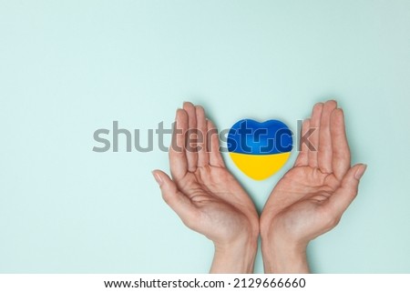 Heart with print the national flag of ukraine in female hands. Flat lay. Royalty-Free Stock Photo #2129666660