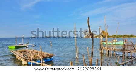 A small boat on a beach in Jepara, used for fishing. In the picture there is also a small artificial dock made of a series of wood.