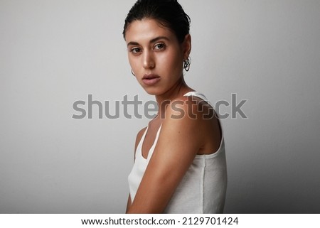 Portrait of young confident woman looking at the camera on white background.