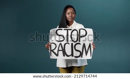 An attractive african lady is showing a poster, calling on everyone to stop racism and moving away