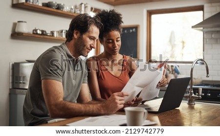 Our debt is almost paid off. Cropped shot of a couple using their laptop and going through paperwork at home. Royalty-Free Stock Photo #2129742779