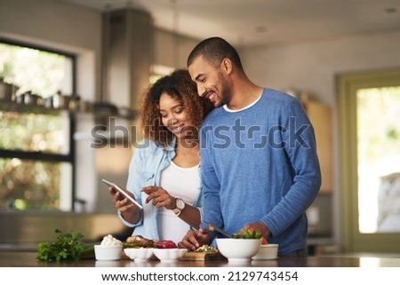 Using a step by step online recipe. Shot of a happy young couple using a digital tablet while preparing a healthy meal together at home.