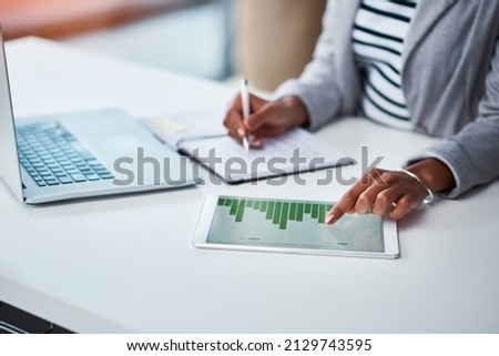 Making money work for her business. Shot of an unrecognizable businesswoman using a digital tablet with graphs on it in a modern office. Royalty-Free Stock Photo #2129743595