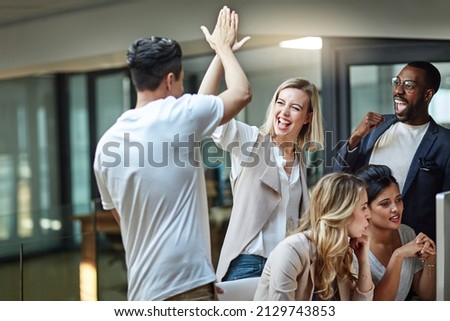 Weve done it again. Shot of a group of colleagues giving each other a high five while using a computer together at work. Royalty-Free Stock Photo #2129743853