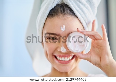 Keep your skin healthy. Cropped portrait of a beautiful young woman applying moisturizer to her skin in the bathroom at home. Royalty-Free Stock Photo #2129744405