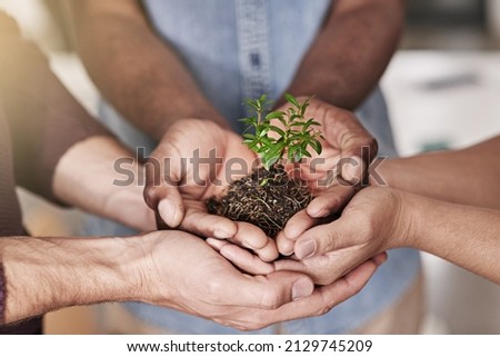 Committed to making their new business flourish. Cropped shot of a group of people holding a plant growing out of soil. Royalty-Free Stock Photo #2129745209