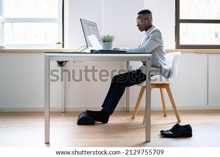 Worker Using Footrest To Reduce Back Strain And Feet Fatigue Royalty-Free Stock Photo #2129755709