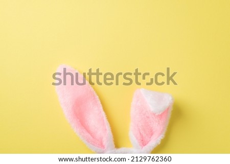 Top view photo of the white and pink tender headband in shape of rabbits ears on the isolated yellow background blank space