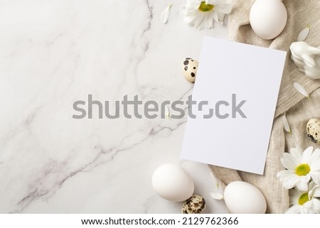 Top view photo of the postcard three daisies and few eggs and ceramic rabbit on textile on isolated marble empty background