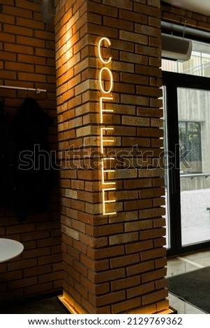 Coffee neon sign emblem in neon style on brick wall background. Coffee shop