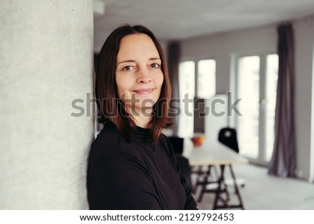 Portrait of brunette woman leaning on column at home