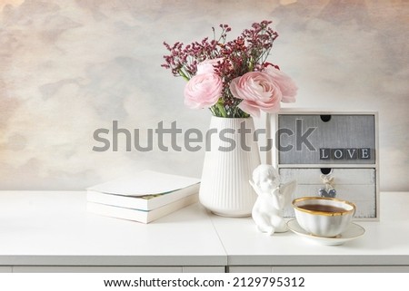 Feminine wedding or birthday table mockup scene with floral bouquet.  greeting card, cup of coffee and books. Royalty-Free Stock Photo #2129795312