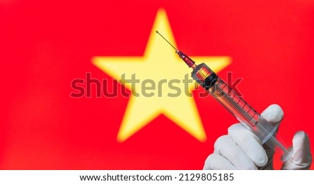 Vaccination is a common practice in Vietnam. On the background of a country flag, a vaccine to protect against Covid-19.