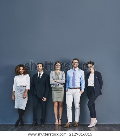 Corporate confidence at its best. Studio shot of a group of businesspeople standing in line against a gray background. Royalty-Free Stock Photo #2129816015
