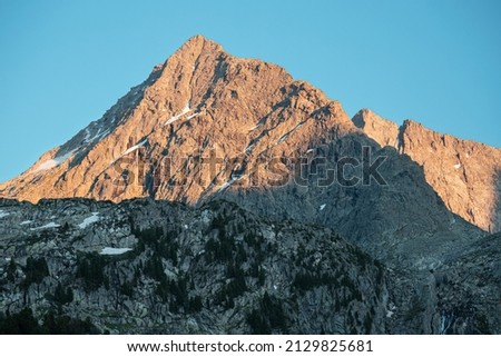The rocky peak of the mountain is illuminated by the last red reflections from the sun. Moody picture