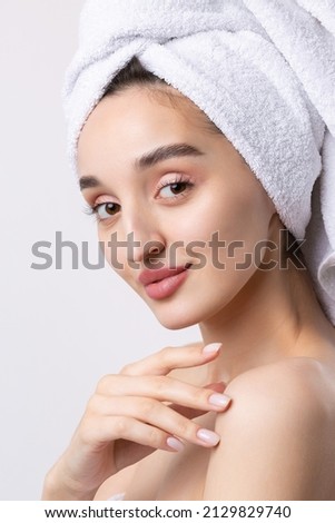 Beautiful girl with thick eyebrows and perfect skin at white background, towel on head, beauty photo.