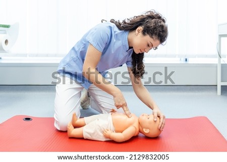 Woman performing CPR on baby training doll with one hand compression. First Aid Training - Cardiopulmonary resuscitation. First aid course on cpr dummy. Royalty-Free Stock Photo #2129832005