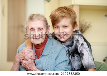 The boy hugs his grandmother, strong family ties, care for the older generation, grandson and great-grandmother at home. Royalty-Free Stock Photo #2129832350