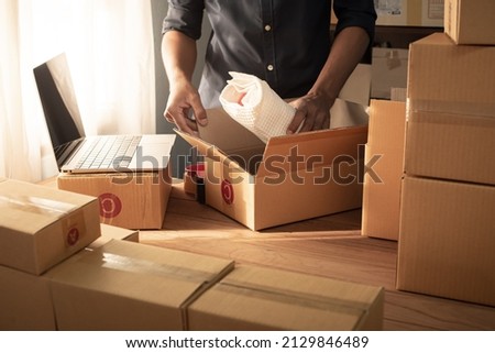 Small business owner packing in the cardbox at workplace. Cropped shot of man preparing a parcel for delivery at online selling business office. Ecommerce drop shipping shipment service concept. Royalty-Free Stock Photo #2129846489