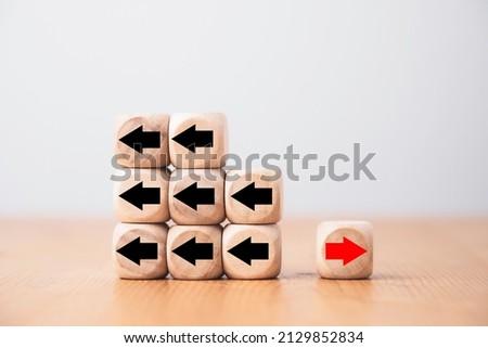 Red arrow on wooden move on different direction with black arrow on cube for business and technology disruption or unique concept.
