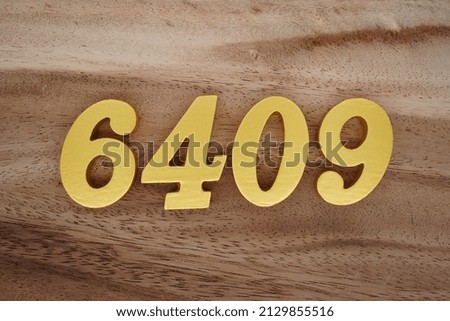 Wooden  numerals 6409 painted in gold on a dark brown and white patterned plank background.