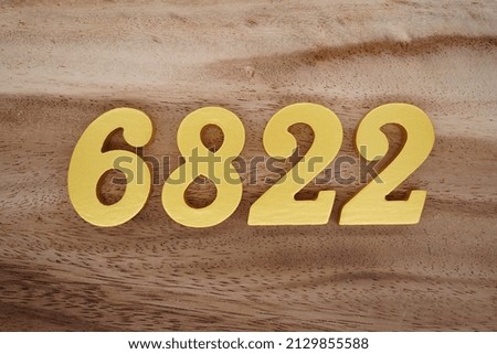 Wooden  numerals 6822 painted in gold on a dark brown and white patterned plank background.