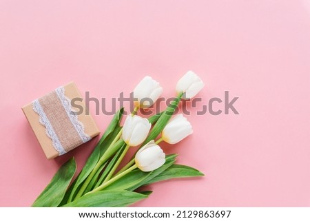 Gift box and bouquet of white tulips on pink background. Women's day, Mother's day, spring concept. Top view, flat lay, copy space.