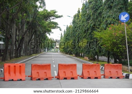 Orange plastic barrier on highway asphalt, blocking traffic on road. Closed section.