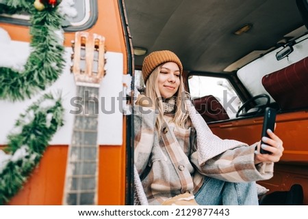 Young caucasian woman taking selfie photo, sitting in a car while traveling in road trip.