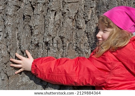 Child hugs a big tree 