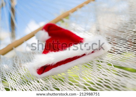 vacation, christmas and holiday concept - picture of hammock with santa helper hat