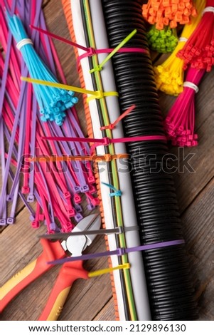 colored plastic clamps tightening wires and corrugation, pieces on the table of old boards. plastic ties for wires and cables. Royalty-Free Stock Photo #2129896130