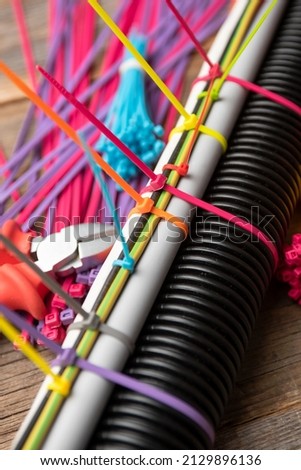 colored plastic clamps tightening wires and corrugation, pieces on the table of old boards. plastic ties for wires and cables. Royalty-Free Stock Photo #2129896136