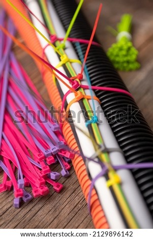 colored plastic clamps tightening wires and corrugation, pieces on the table of old boards. plastic ties for wires and cables. Royalty-Free Stock Photo #2129896142