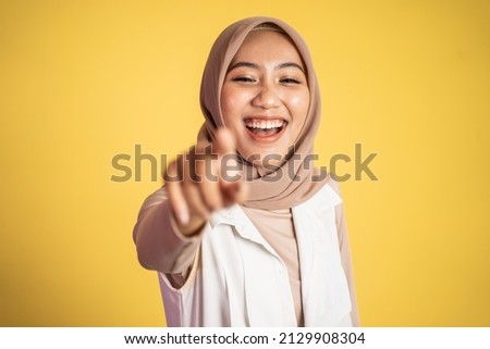 muslim woman with finger pointing laughing at something