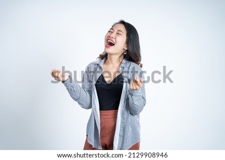 laughing young woman clenching hands while celebrating success