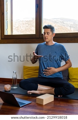 Pranayama and meditation teacher in an online class, teaching his students how to inhale. Royalty-Free Stock Photo #2129918018