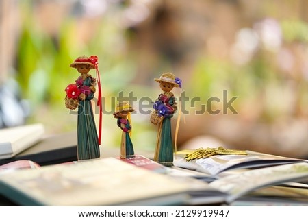 Three female dolls made of dry straw, decorate a work desk on a blurred background.                               